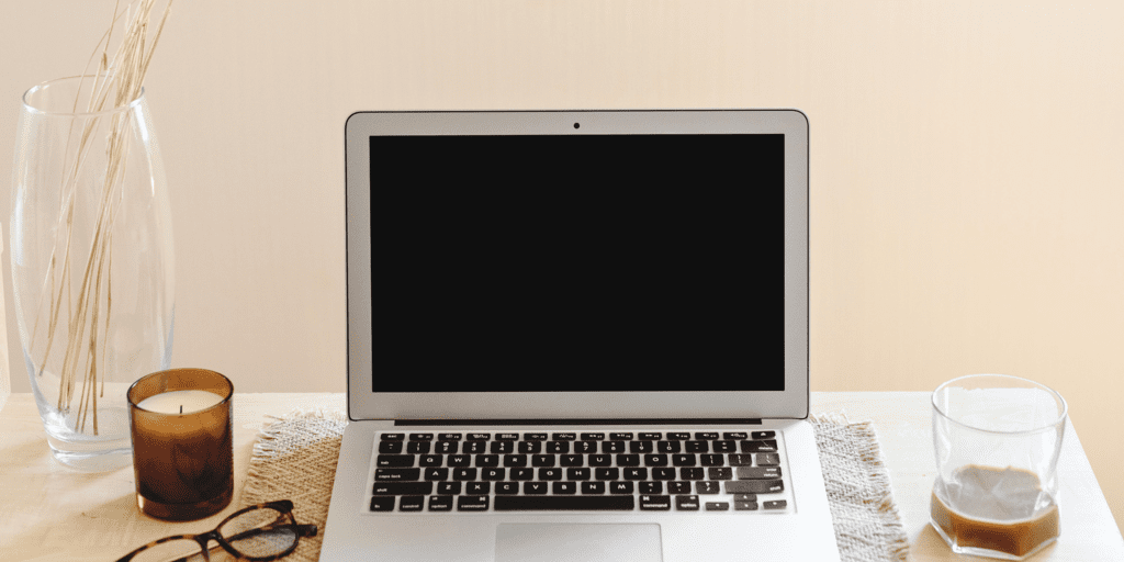 a laptop on a table with a candle and a cup of coffee