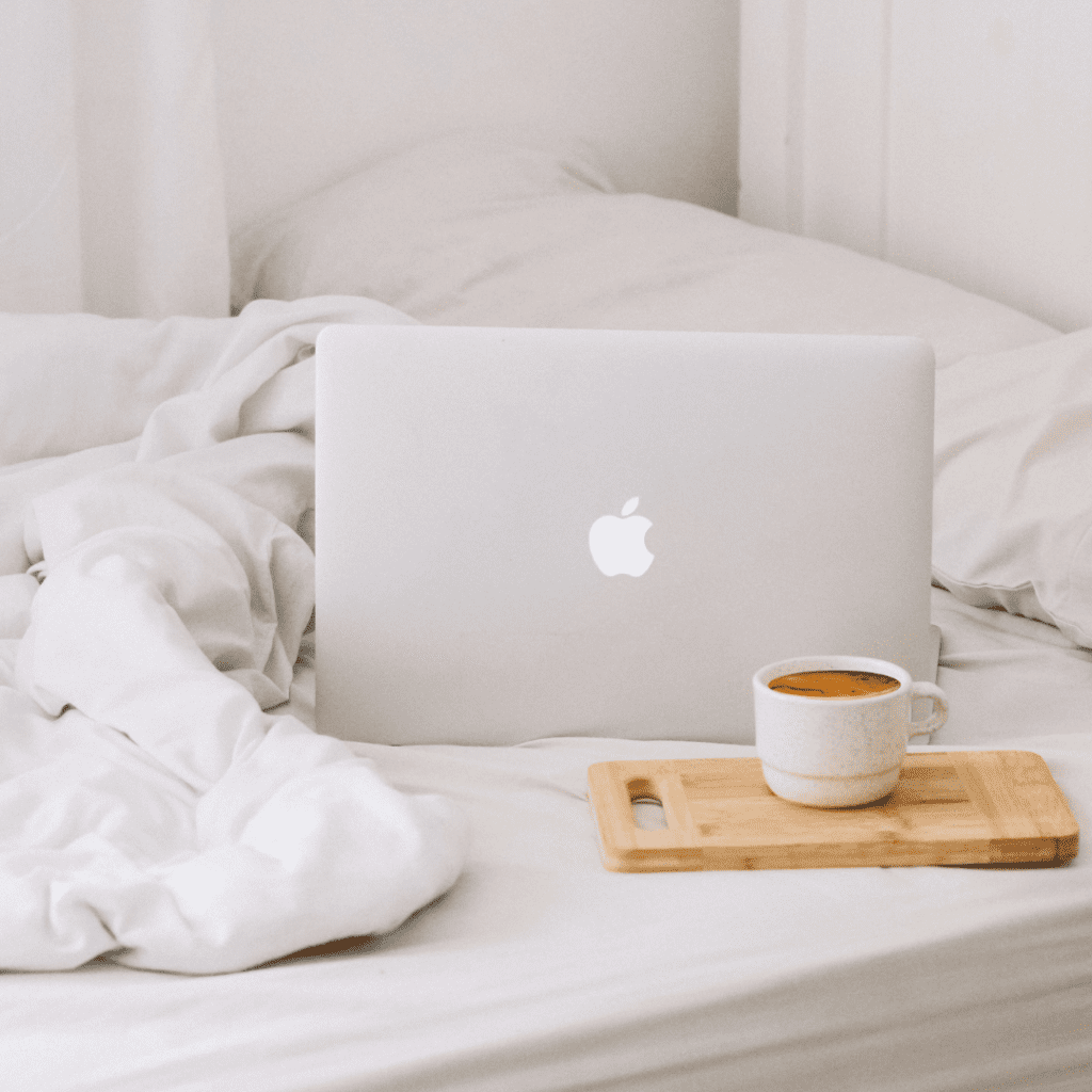 laptop on a bed with a cup of coffee, image for home page